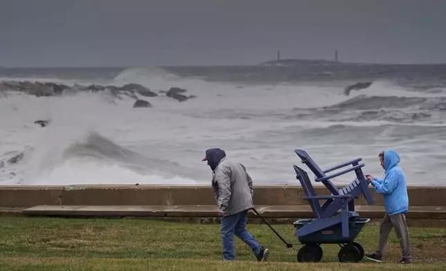 Chuck and Teresa Palmieri move lawn furniture to a safe location at a relative's seaside property as the Atlantic Ocean kicks up surf during the early stages of a nor'easter storm, Friday, Sept. 25, 2026, in Gloucester, Mass. (AP Photo/Robert F. Bukaty)