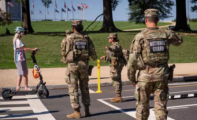 National Guard troops stop a young woman on a rental scooter near a closed intersection where President Donald Trump was holding an event, in Washington, Tuesday, Sept. 8, 2026. (AP Photo/J. Scott Applewhite)