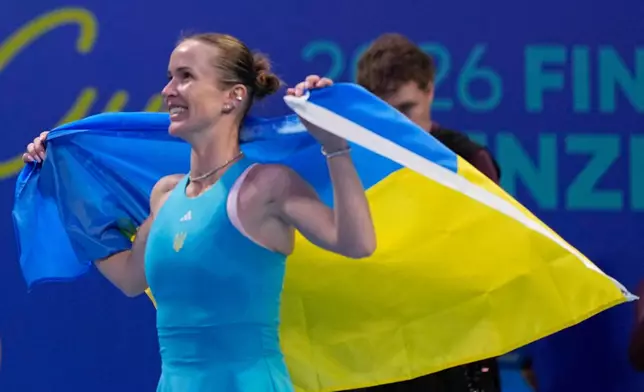 Elina Svitolina of Ukraine celebrates with the Ukraine flag after defeating Jasmine Paolini of Italy during the semifinal match of the Billie Jean King Cup in Shenzhen in southern China's Guangdong province, Saturday, Sept. 26, 2026. (AP Photo/Andy Wong)