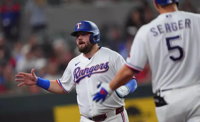 Texas Rangers' Jake Burger, left, celebrates scoring on an Evan Carter force out grounder during the fifth inning of a baseball game against the New York Mets, Wednesday, Sept. 23, 2026, in Arlington, Texas. (AP Photo/LM Otero)