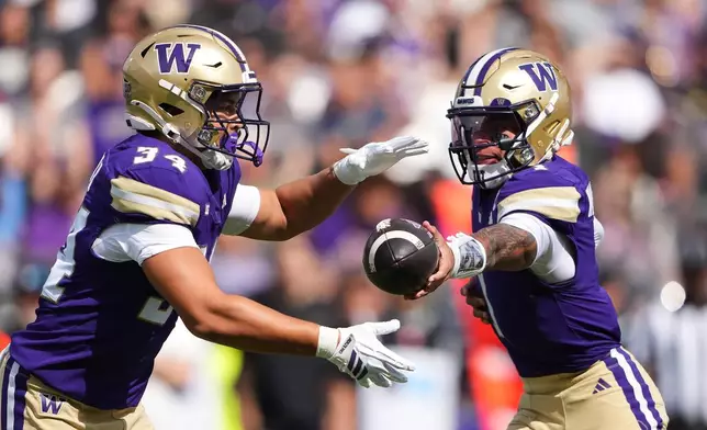 Washington quarterback Demond Williams Jr., right, hands off the ball to running back Brian Bonner, left, during the first half of an NCAA college football game against Utah State Saturday, Sept. 12, 2026, in Seattle. (AP Photo/Lindsey Wasson)
