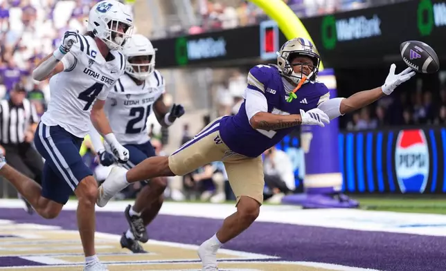 Washington wide receiver Dezmen Roebuck (2) can't bring in a pass in the end zone against Utah State safety Brevin Hamblin (4) during the first half of an NCAA college football game Saturday, Sept. 12, 2026, in Seattle. (AP Photo/Lindsey Wasson)