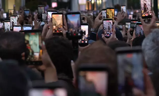 Members of the crowd take pictures and video on their phones as they watch U2 perform an impromptu concert from a balcony in central Dublin, Ireland, Friday, Sept. 25, 2026. (AP Photo/Peter Morrison)