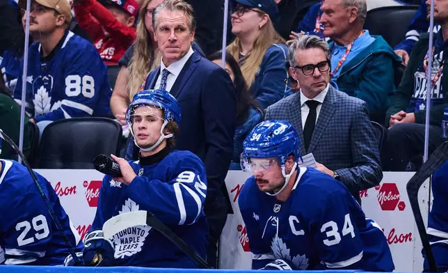 Toronto Maple Leafs head coach Jim Hiller, top left, looks on past Gavin McKenna (92), left, and Auston Matthews (34) during second period NHL pre-season hockey action against the Montreal Canadiens in Toronto, on Saturday, Sept. 19, 2026. (Sammy Kogan/The Canadian Press via AP)