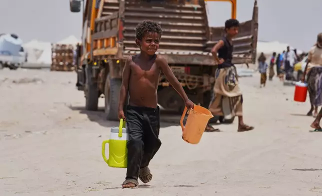A displaced Yemeni boy carries water containers at Al-Firdaws camp in Ras Imran, on the western outskirts of Aden, Yemen, Tuesday, Sept. 29, 2026. (AP Photo/Abdulnasser Alseddik)