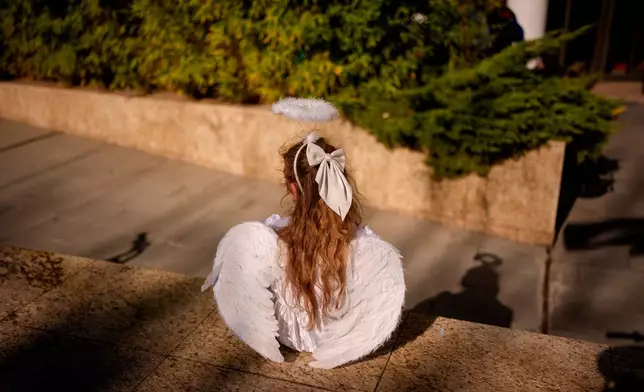 A child dressed as an angel sits during an event dubbed the Little Angels' Parade, a Christian-themed street performance featuring dozens of children wearing angel costumes, in Bucharest, Romania, Saturday, Sept. 5, 2026. Sept. 5, 2026. (AP Photo/ Andreea Alexandru)
