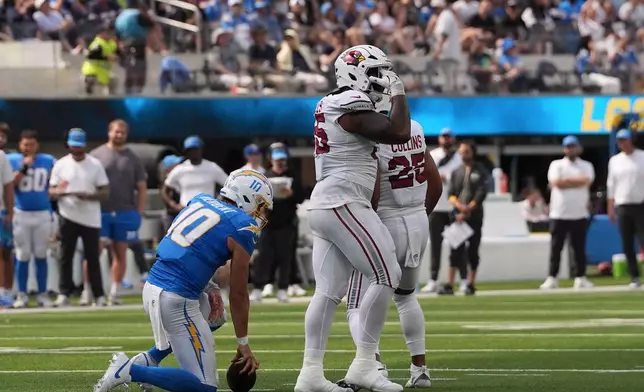 Arizona Cardinals defensive tackle Dante Stills, middle, reacts after sacking Los Angeles Chargers quarterback Justin Herbert (10) on fourth down during the first half of an NFL football game, Sunday, Sept. 13, 2026, in Inglewood, Calif. (AP Photo/Gregory Bull)