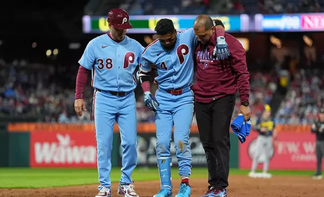 Philadelphia Phillies' Luis Arraez (4) is helped off the field after being injured during the sixth inning of a baseball game against the Milwaukee Brewers, Thursday, Sept. 24, 2026, in Philadelphia. (AP Photo/Matt Rourke)