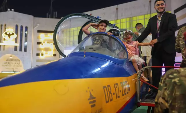 A boy salutes from the cockpit of an aircraft on display at the 63rd Damascus International Fair in Damascus, Syria, Monday, Aug. 31, 2026. (AP Photo/Ghaith Alsayed)