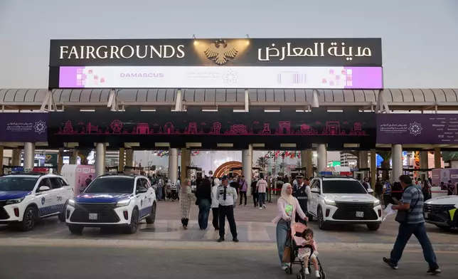 Visitors walk past police vehicles at the entrance to the 63rd Damascus International Fair on the outskirts of Damascus, Syria, Monday, Aug. 31, 2026. (AP Photo/Ghaith Alsayed)