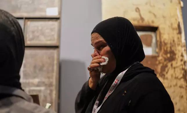 A woman becomes emotional while viewing a display using original items from Syria's Saydnaya prison to recreate a cell as it appeared during the rule of former President Bashar Assad at "When the Walls Speak," an exhibit at the Damascus International Fair in Damascus, Syria, Monday, Aug. 31, 2026. (AP Photo/Ghaith Alsayed)
