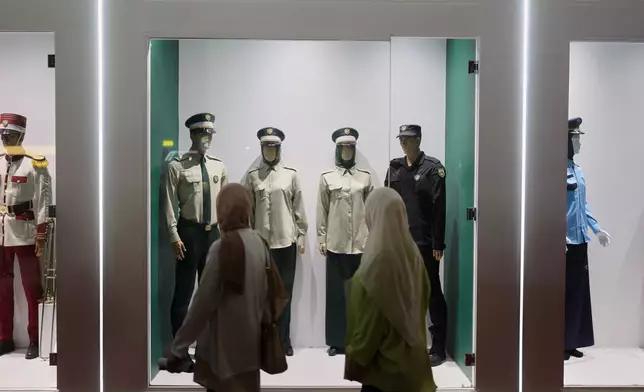 Visitors walk past Syrian police uniforms on display at the 63rd Damascus International Fair on the outskirts of Damascus, Syria, Monday, Aug. 31, 2026. (AP Photo/Ghaith Alsayed)
