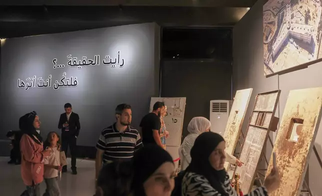 Visitors view cell doors displayed at "When the Walls Speak," an exhibit at the Damascus International Fair that recreates Syrian prisons during the rule of former President Bashar Assad, in Damascus, Syria, Monday, Aug. 31, 2026.(AP Photo/Ghaith Alsayed)