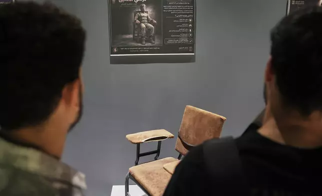 Visitors view a chair presented as having been used to torture detainees at Syria's Saydnaya prison at "When the Walls Speak," an exhibit at the Damascus International Fair featuring items from prisons during the rule of former President Bashar Assad, in Damascus, Syria, Monday, Aug. 31, 2026. (AP Photo/Ghaith Alsayed)