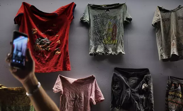 A visitor photographs clothes found at prisons and displayed at "When the Walls Speak," an exhibit at the Damascus International Fair featuring items from prisons during the rule of former President Bashar Assad, in Damascus, Syria, Monday, Aug. 31, 2026. (AP Photo/Ghaith Alsayed)
