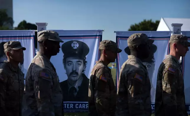 U.S. Army soldiers walk past a portrait of New York firefighter Peter Carroll at a Steel Across America event with the Tunnel to Towers Foundation on the Ellipse, Tuesday, Sept. 8, 2026, in Washington. (AP Photo/Mark Schiefelbein)