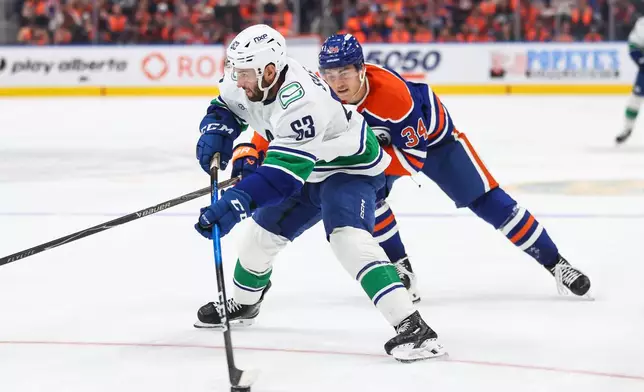 Vancouver Canucks' Max Sasson (63) is pursued by Edmonton Oilers' Colton Dach (34) during third period NHL hockey action in Edmonton on Tuesday, Sept. 29, 2026. (Codie McLachlan/The Canadian Press via AP)