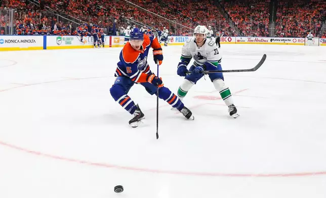 Edmonton Oilers' Connor Murphy (5) defends against Vancouver Canucks' Marco Rossi (23) during third period NHL hockey action in Edmonton on Tuesday, Sept. 29, 2026. (Codie McLachlan/The Canadian Press via AP)