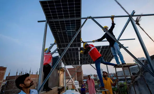 FILE - Workers install solar panels on a rooftop of a home in Prayagraj, India, Monday, Oct. 14, 2024. (AP Photo/Rajesh Kumar Singh, File)