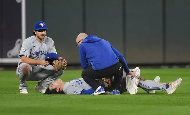 Toronto Blue Jays center fielder Brett Bateman, center, is tended to by a trainer, right, after an injury during the second inning of a baseball game against the Baltimore Orioles, Monday, Sept. 21, 2026, in Baltimore. (AP Photo/Stephanie Scarbrough)