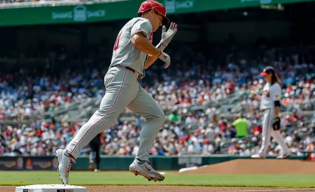 Philadelphia Phillies' J.T. Realmuto, left, reacts while rounding the bases after hitting a two-run home run off Atlanta Braves pitcher Grant Holmes, back right, during the second inning of a baseball game, Sunday, Sept. 13, 2026, in Atlanta. (AP Photo/Erik S. Lesser)