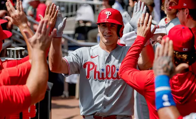 Philadelphia Phillies' J.T. Realmuto is greeted in the dugout after hitting a two-run home run against the Atlanta Braves during the second inning of a baseball game, Sunday, Sept. 13, 2026, in Atlanta. (AP Photo/Erik S. Lesser)