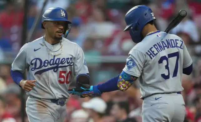 Los Angeles Dodgers' Mookie Betts (50) celebrates with Teoscar Hernández (37) after scoring on a double hit by Will Smith during the third inning of a baseball game against the Cincinnati Reds, Wednesday, Sept. 16, 2026, in Cincinnati. (AP Photo/Carolyn Kaster)