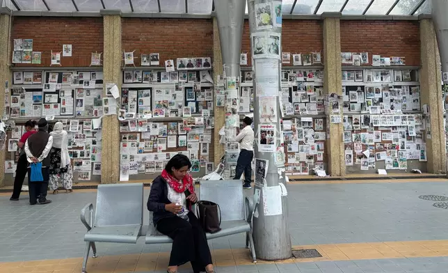 In this photo taken with a smartphone, people look at photographs of hundreds of people missing since last month’s floods, posted on a wall by relatives hoping to receive information about them at Tribhuvan University Teaching Hospital, in Kathmandu, Nepal, Thursday, Sept. 17, 2026. (AP photo/Upendra Man Singh)