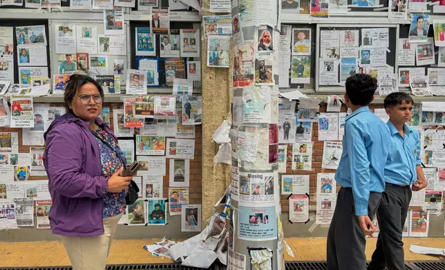 In this photo taken with a smartphone, people look at photographs of hundreds of people missing since last month’s floods, posted on a wall by relatives hoping to receive information about them at Tribhuvan University Teaching Hospital, in Kathmandu, Nepal, Thursday, Sept. 17, 2026. (AP photo/Upendra Man Singh)
