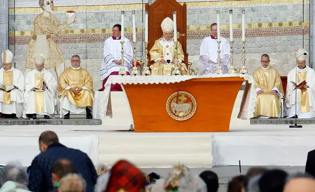FILE - Pope Benedict XVI, center, celebrates a Mass in front of the Basilica of the Rosary in Lourdes, southwestern France, on Sept. 15, 2008. Behind him is one of the mosaics by Rev. Marko Ivan Rupnik, who was declared excommunicated in 2020 for committing one of the worst crimes in church law – using the confessional to absolve a woman with whom he had engaged in sexual activity. (AP Photo/Alessandra Tarantino, File)