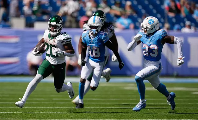 New York Jets running back Breece Hall (20) runs for a first down pursued by Tennessee Titans cornerback Cor'dale Flott (18) and safety Kevin Winston Jr. (23) during the second half of an NFL football game, Sunday, Sept. 13, 2026, in Nashville, Tenn. (AP Photo/George Walker IV)