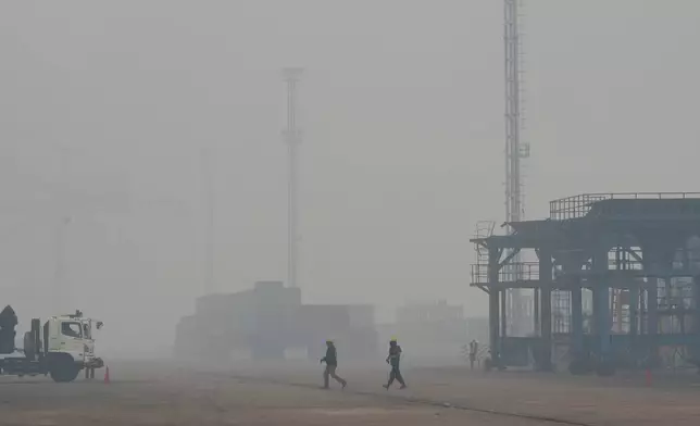 Dock workers walk amid the thick haze from forest fires at Kijing Port in Mempawah, West Kalimantan, Indonesia, Thursday, Sept. 10, 2026. (AP Photo/Tatan Syuflana)
