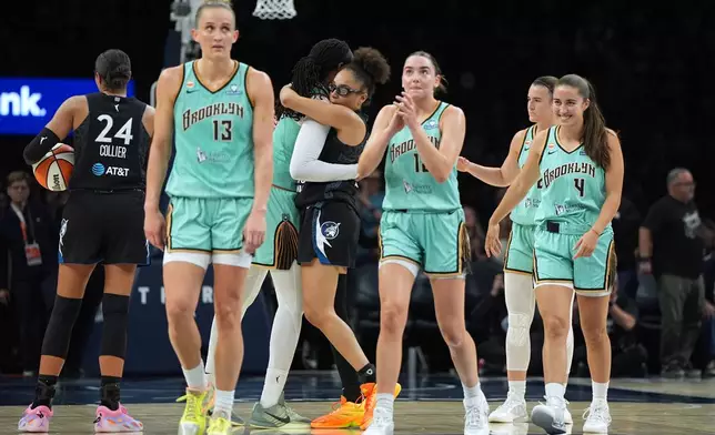 Minnesota Lynx guard Olivia Miles, center right, and New York Liberty center Jonquel Jones, center left, hug during the final seconds of a WNBA basketball game Friday, Sept. 18, 2026, in Minneapolis. (AP Photo/Abbie Parr)