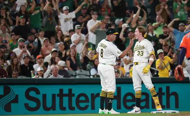 Athletics third base coach Bobby Crosby (8) congratulates Henry Bolte (33) after Bolte hit a two-RBI triple during the sixth inning of a baseball game against the Houston Astros, Friday, Sept. 25, 2026, in West Sacramento, Calif. (AP Photo/Sara Nevis)