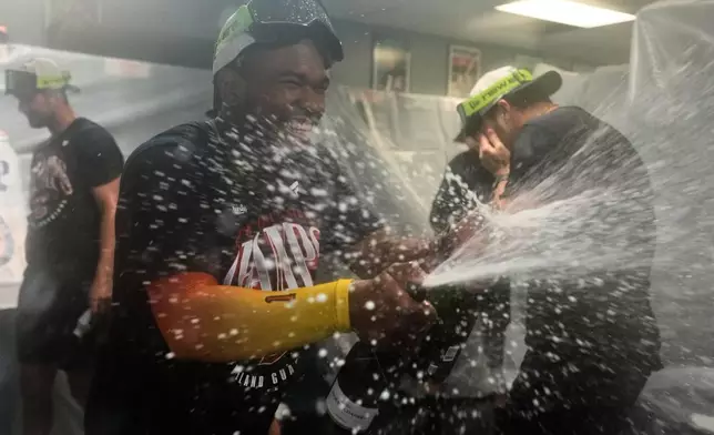 Cleveland Guardians' Angel Martinez celebrates in the clubhouse with teammates after clinching the American League Central division title by defeating the Kansas City Royals in a baseball game Saturday, Sept. 26, 2026, in Kansas City, Mo. (AP Photo/Charlie Riedel)