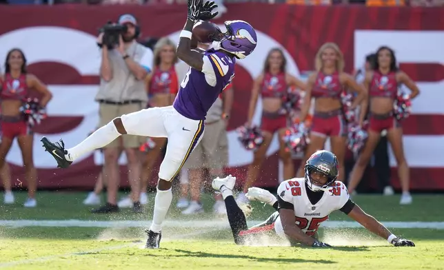 Minnesota Vikings wide receiver Jordan Addison (3) catches a pass for a touchdown as Tampa Bay Buccaneers cornerback Jacob Parrish (25) defends during the first half of an NFL football game in Tampa, Fla., Sunday, Sept. 27, 2026. (AP Photo/Chris O'Meara)