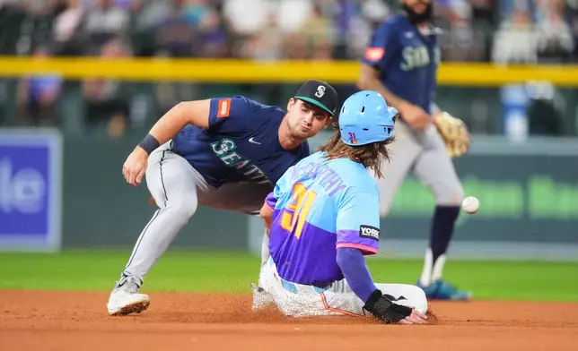 Seattle Mariners second baseman Cole Young, left, misses a pickoff throw as Colorado Rockies' Jake McCarthy, right, steals second in the fourth inning of a baseball game Friday, Sept. 18, 2026, in Denver. (AP Photo/David Zalubowski)