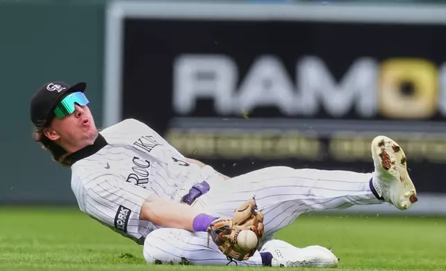 Colorado Rockies left fielder Jake McCarthy tries to catch an RBI single off the bat of Arizona Diamondbacks' Geraldo Perdomo in the second inning of a baseball game Thursday, Sept. 24, 2026, in Denver. (AP Photo/David Zalubowski)
