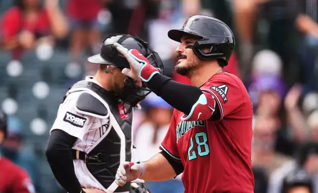 Arizona Diamondbacks' Nolan Arenado, front, gestures as he crosses home plate after hitting a two-run home run as Colorado Rockies catcher Brett Sullivan waits for play to resume in the first inning of a baseball game Thursday, Sept. 24, 2026, in Denver. (AP Photo/David Zalubowski)