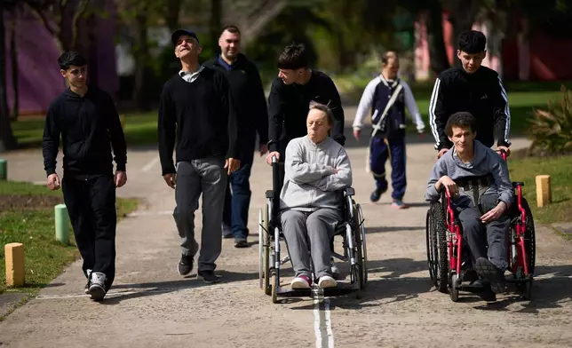 Volunteers go for a walk with residents at the Pequeño Cottolengo Don Orione, a home for people with disabilities that will be visited by Pope Leo XIV in November, in Buenos Aires, Argentina, Thursday, Sept. 24, 2026. (AP Photo/Rodrigo Abd)
