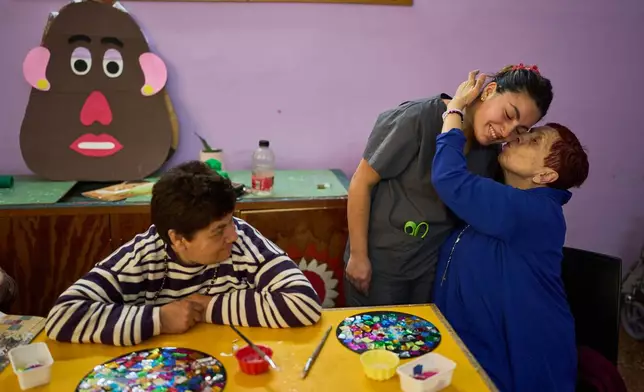 Stella Maris Fernandez kisses instructor Lucia Carrera while taking part in an art workshop at the Pequeño Cottolengo Don Orione, a home for people with disabilities that will be visited by Pope Leo XIV in November, in Buenos Aires, Argentina, Thursday, Sept. 24, 2026. (AP Photo/Rodrigo Abd)