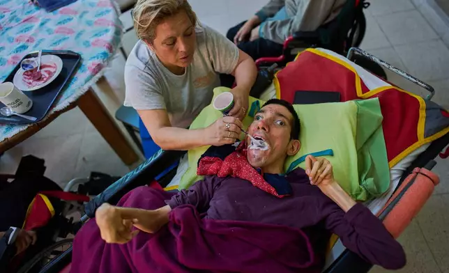 Employee Nancy Bravo feeds resident Miguel Rojas in the Pequeño Cottolengo Don Orione, a home for people with disabilities that will be visited by Pope Leo XIV in November, in Buenos Aires, Argentina, Thursday, Sept. 24, 2026. (AP Photo/Rodrigo Abd)