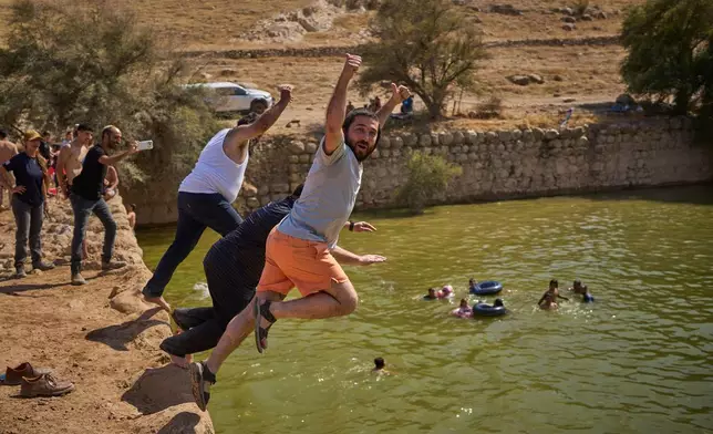 Israeli Knesset member Zvi Sukkot, right, and Minister of Heritage Amichai Eliyahu jump into a pool at an ancient archaeological site known as Herod's Pool, near the Israeli settlement of Petzael, in the occupied West Bank, on June 19, 2026. (AP Photo/Ohad Zwigenberg)