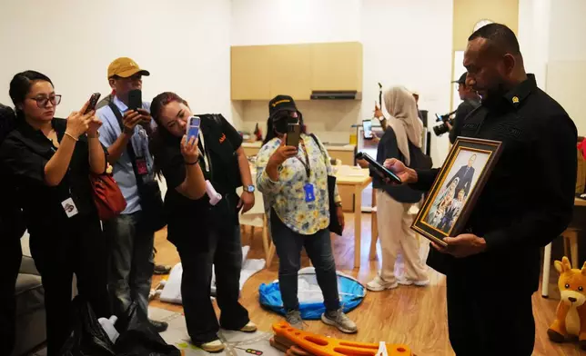 A lawmaker shows journalists a framed family photograph at a controversial luxury compound inside a penitentiary in Cibinong Prison in Bogor, West Java, Indonesia, Wednesday, Sept. 30, 2026. (AP Photo/Tatan Syuflana)
