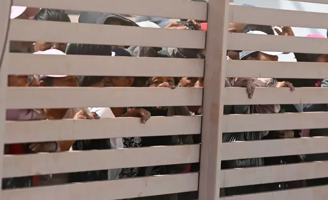Relatives of crew members of the boat Maria Candelaria peer through a fence outside a police facility in Manta, Ecuador, Monday, Sept. 7, 2026, as they wait for the crew to return after the boat was intercepted by U.S. authorities on suspicion of alleged drug trafficking. (AP Photo/Ariel Ochoa)
