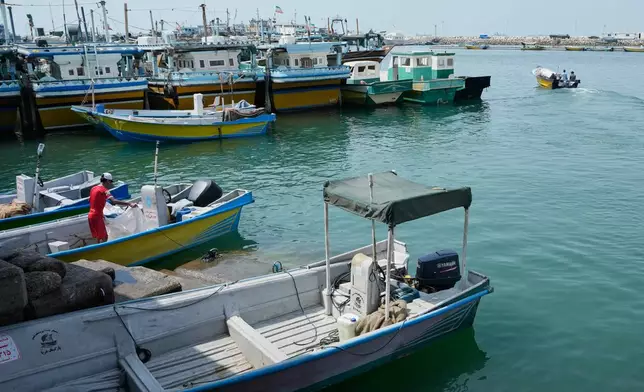 A man works aboard a boat as a motorboat leaves a harbor in Bandar Abbas, Iran, Sunday, Sept. 6, 2026. (AP Photo/Vahid Salemi)