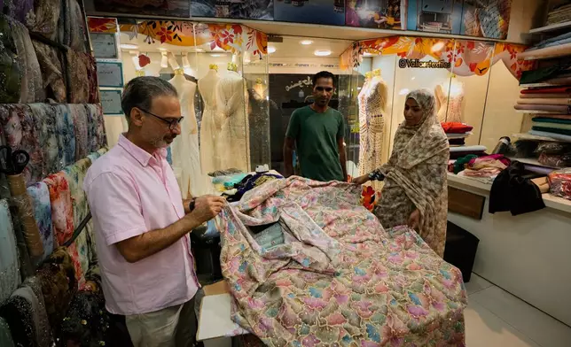 People examine embroidered fabric at a textile shop in a traditional bazaar in Bandar Abbas, Iran, Sunday, Sept. 6, 2026. (AP Photo/Vahid Salemi)