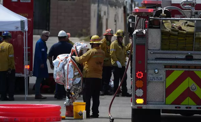 A fire fighter is assisted in removing his hazmat suit following a reported chemical leak, Tuesday, Sept. 8, 2026, in La Habra, southern Calif. (AP Photo/Jae C. Hong)