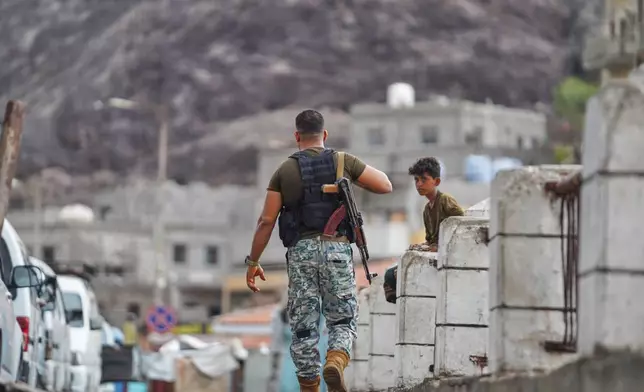 An armed man walks past a boy at the Sirah fish market in Aden, Yemen, Tuesday, Sept. 15, 2026. (AP Photo/Abdulnasser Alseddik)