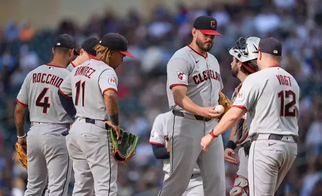 Cleveland Guardians relief pitcher Franco Aleman, middle, right, hands the game ball to manager Stephen Vogt (12) for a pitching change during the third inning of a baseball game against the Minnesota Twins Saturday, Sept. 12, 2026, in Minneapolis. (AP Photo/Abbie Parr)